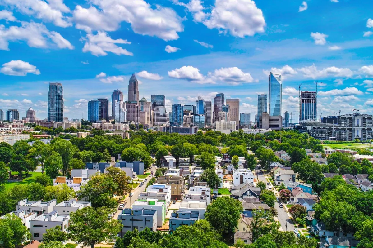 A panoramic city view showcasing the Charlotte skyline, green parks, and nearby residential neighborhoods. The image suggests opportunities for exploration, outdoor activities, and community engagement.