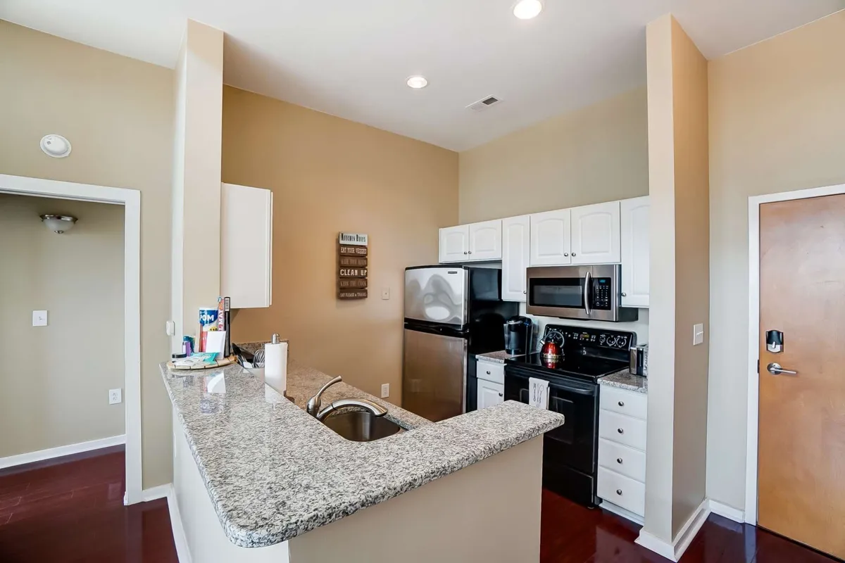 This image features a kitchen with granite countertops, stainless steel appliances, and white cabinetry. The focal area shows ample counter space for meal preparation and modern fixtures, capturing a cozy and inviting setting ideal for cooking and entertaining.